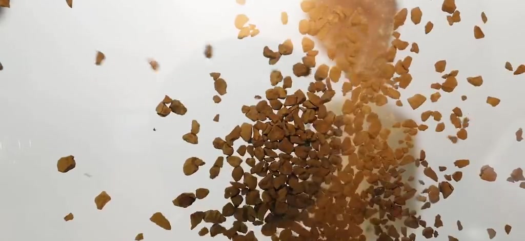 Freeze-dried instant coffee granules in motion during product handling